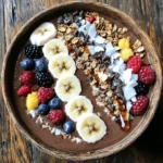 To make a delicious High-Protein Mocha Smoothie Bowl, gather these ingredients: - 1 cup unsweetened almond milk - 1 frozen banana - 1 scoop chocolate protein powder - 2 tablespoons cold brew coffee - 1 tablespoon unsweetened cocoa powder - 1 tablespoon almond butter - 1 tablespoon chia seeds - 1 teaspoon honey or maple syrup (optional, for sweetness) These ingredients create a rich and creamy base. The frozen banana adds natural sweetness and creaminess. The chocolate protein powder gives a protein boost and chocolate flavor, while cold brew coffee adds a nice kick. Cocoa powder deepens the chocolate taste. Almond butter brings healthy fats, and chia seeds add fiber and texture. You can use honey or maple syrup if you want it sweeter. Choosing the right toppings makes your smoothie bowl even better. Here are some great options: - Sliced banana - Granola - Cacao nibs - Coconut flakes - Mixed berries These toppings add crunch, flavor, and color. Sliced banana enhances the banana taste. Granola gives a nice crisp texture. Cacao nibs add a rich chocolate crunch. Coconut flakes offer a tropical twist, and mixed berries provide a burst of freshness. Feel free to mix and match toppings based on your taste! To start, gather your ingredients. You will need: - 1 cup unsweetened almond milk - 1 frozen banana - 1 scoop chocolate protein powder - 2 tablespoons cold brew coffee - 1 tablespoon unsweetened cocoa powder - 1 tablespoon almond butter - 1 tablespoon chia seeds - 1 teaspoon honey or maple syrup (optional) Combine all these ingredients in your blender. Using a frozen banana is key. It makes your smoothie thick and creamy. Fresh bananas won't give you the same texture. Plus, frozen bananas add a nice chill to your bowl. Now, let's blend! Set your blender to high speed. Blend for about 1-2 minutes. You want a smooth and creamy texture. If you see bits of banana or protein powder, stop and scrape down the sides. Then, blend again until it’s perfect. If your mixture is too thick, add a splash of almond milk to help it blend. Once your smoothie is blended, it’s time to serve. Pour the mixture into a deep bowl. This gives it a nice look. Now, let’s talk toppings! I like to arrange my toppings for a colorful and fun display. You can use: - Sliced banana - A handful of granola - Cacao nibs - Coconut flakes - Mixed berries Take your time to make it pretty. A well-arranged bowl is not just tasty; it's also fun to eat. Grab a spoon and enjoy your high-protein mocha smoothie bowl right away! You can boost your smoothie bowl's health with great ingredients. Consider adding spinach or kale. These greens blend well and add vitamins. You can also use hemp seeds for extra protein. They have a nutty flavor and mix easily. If you want fiber, try adding oats. This will make your bowl more filling. If you want less sugar, try using stevia or monk fruit. These sweeteners keep the taste sweet without adding calories. You can also enhance flavors with spices. A pinch of cinnamon or nutmeg adds warmth. For a richer taste, try vanilla extract or a dash of espresso powder. These will elevate your smoothie bowl. A good blender makes a big difference. For smooth results, use a high-speed blender. Brands like Vitamix or Blendtec are great choices. They can blend tough ingredients like frozen fruit and seeds. If you have a lower-powered blender, blend in small batches. This will help avoid any chunks in your smoothie. {{image_4}} You can switch up the protein powder for more fun. Try vanilla or even peanut butter protein. Each choice will change the taste. If you want to add seasonal fruits, think about berries in summer or apples in fall. These fruits not only add flavor but also extra nutrients. If you need vegan options, use plant-based protein powder. Almond milk is already vegan, so you’re good there. For gluten-free choices, ensure your toppings are gluten-free. If you have nut allergies, skip almond butter. You can use sunflower seed butter instead. This swaps out the nuts while keeping it creamy. You can pair your mocha smoothie bowl with other bowls for a fun breakfast. Try a berry smoothie bowl or a green smoothie bowl. Mixing flavors makes breakfast exciting and colorful. Don’t be afraid to get creative with textures and tastes! To keep your smoothie bowl fresh, store the base in the fridge. Place it in an airtight container. It lasts about 1-2 days. If you add toppings, store them separately. This keeps them crunchy and fresh. Meal prep makes life easier. You can blend the smoothie base and store it. Freeze the base in portions. Use freezer-safe jars or silicone bags. They save space and prevent freezer burn. Label the containers with the date to track freshness. When you want to enjoy your leftovers, take them out of the freezer. Thaw it in the fridge overnight. If you’re in a hurry, use the microwave. Heat it in short bursts to avoid overheating. Stir well after heating. You can add fresh toppings before serving. Enjoy your tasty, high-protein mocha smoothie bowl! This smoothie bowl packs a punch! It has around 350 calories per serving. Here's a quick breakdown: - Protein: About 25 grams - Carbohydrates: Roughly 45 grams - Fat: Approximately 10 grams - Fiber: About 8 grams The protein comes mainly from the chocolate protein powder and almond butter. The banana and chia seeds add fiber and healthy carbs. Yes, you can! If you want to swap almond milk, here are some tasty options: - Soy milk: High in protein - Oat milk: Creamy and naturally sweet - Coconut milk: Adds a rich flavor - Cow's milk: Traditional choice with more protein Choose what you like best for your smoothie bowl! Absolutely! Meal prepping this smoothie bowl is easy. Here are some best practices: - Make the base ahead: Blend the ingredients and store in the fridge for up to 2 days. - Prep toppings separately: Keep toppings in small containers to stay fresh. - Assemble when ready: Pour the base into a bowl and add toppings just before eating. This way, you’ll enjoy a fresh and delicious meal any time! Your high-protein mocha smoothie bowl is easy to make and packed with nutrients. We covered key ingredients, topped it off with some delicious options, and explored many fun ways to mix it up. Remember, you can customize flavors and adjust the sweetness to fit your taste. Prepare in advance for a quick meal, and enjoy the smooth, creamy texture. This smoothie bowl is a great addition to your diet anytime you need a nutritious boost. Savor the simple joy of creating and enjoying a healthy treat!